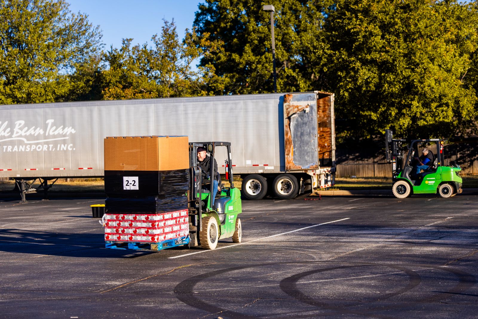 Forklift operators loading a pallet onto a truck at a working freight facility